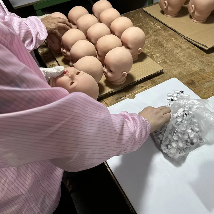 Factory worker hand-finishing a reborn doll